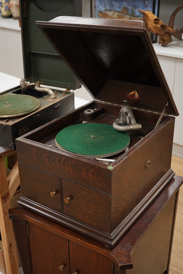 Two gramophone players; an oak cased HMV tabletop gramophone on a similar style mahogany gramophone record stand, height of stand 72.5cm, together with a May-Fair Deluxe Model portable gramophone player. Condition - poor